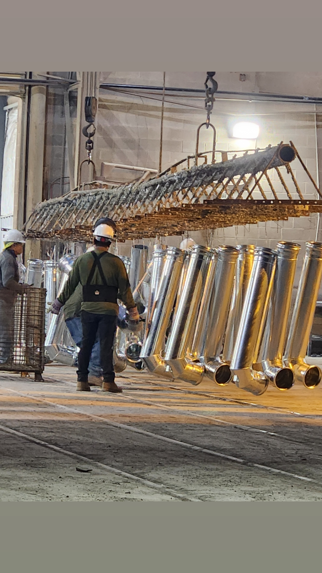 Direct Pivot Parts team handling galvanized center pivot pipe in the workshop