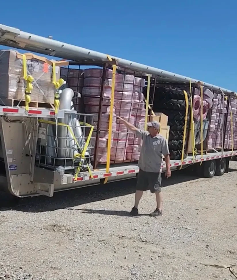 Flatbed truck loaded and strapped with pallets of pivot parts for delivery