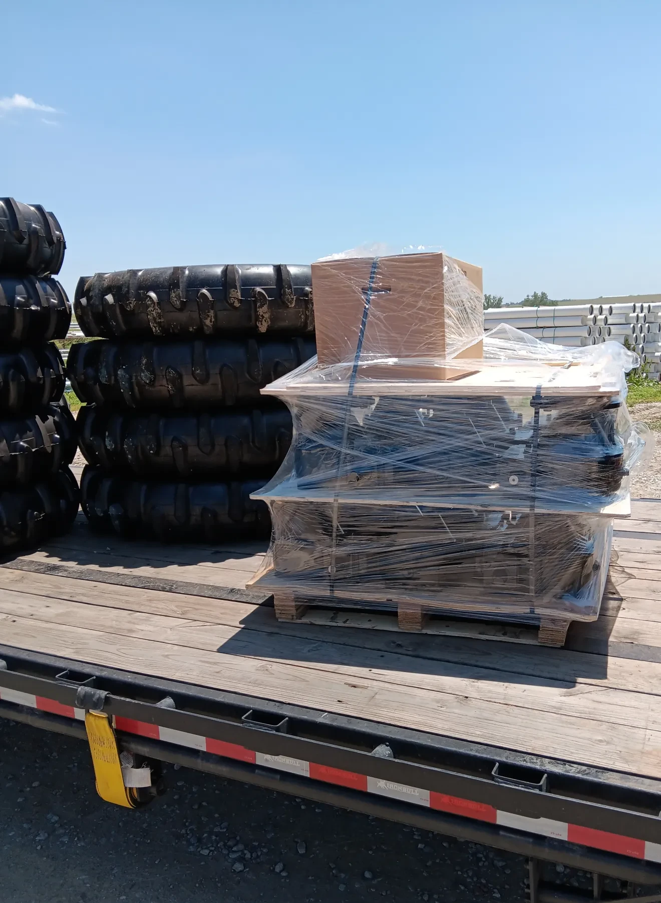 Flatbed trailer of pivot tires and boxed parts secured for international shipping