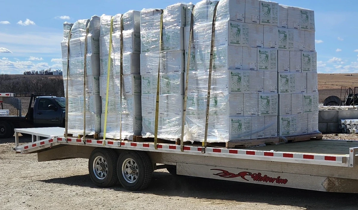 Flatbed trailer loaded with shrink-wrapped pallets of pivot parts